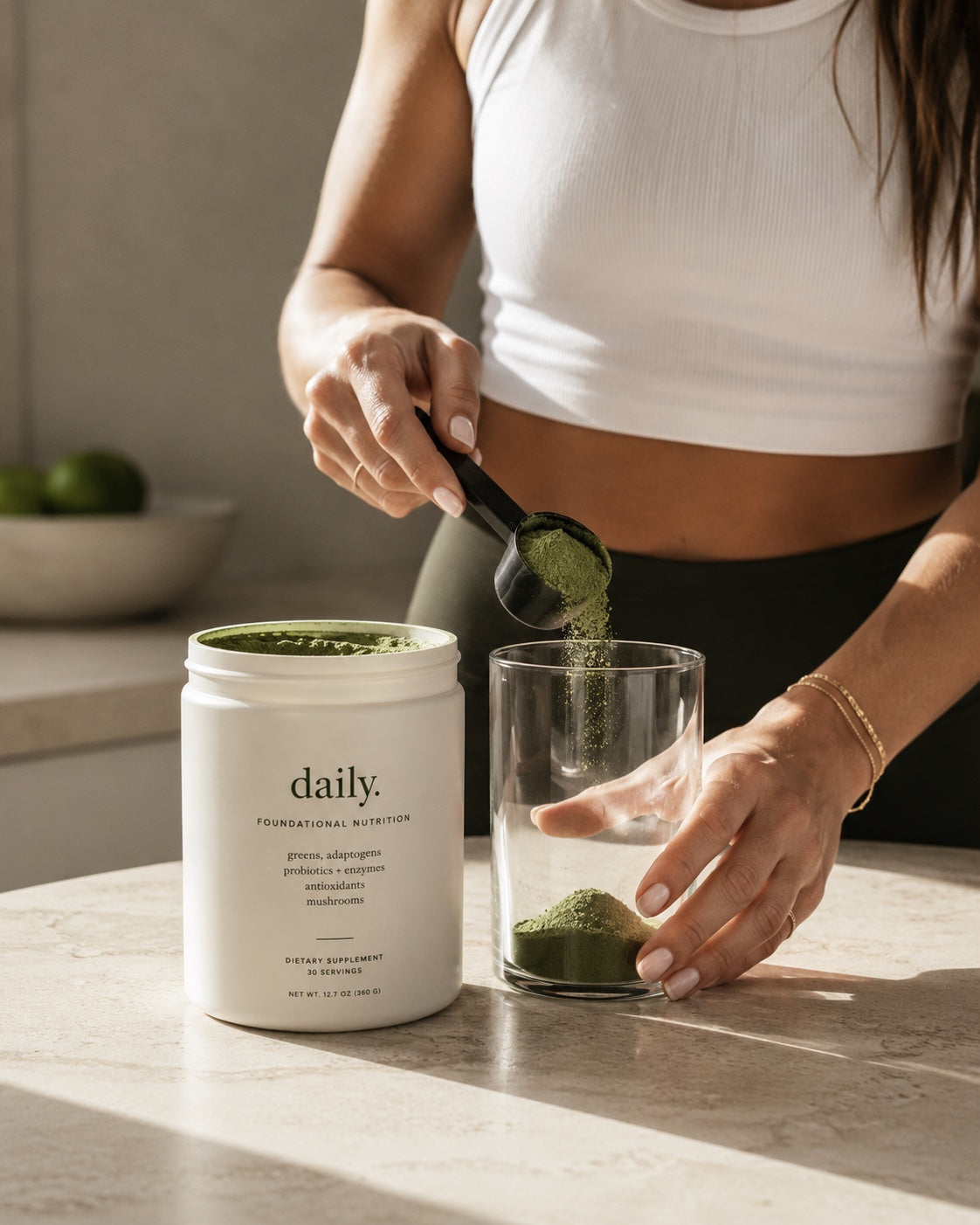 Woman scooping daily. greens into a glass